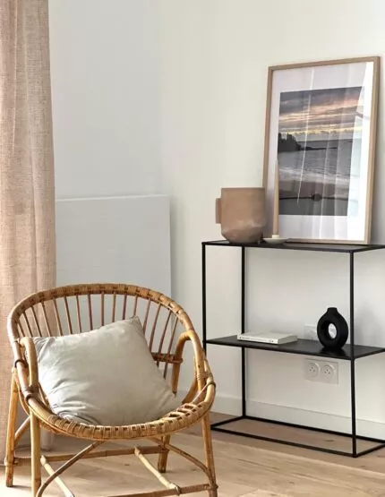 Appartement témoin de la résidence Chemin de la Mer à Dinard. Fauteuil et étagère dans un espace de vie spacieux à la décoration bord de mer.