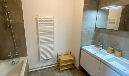 Salle de bain avec baignoire et double vasque d'un appartement neuf à Rennes, dans la résidence Brownstone.