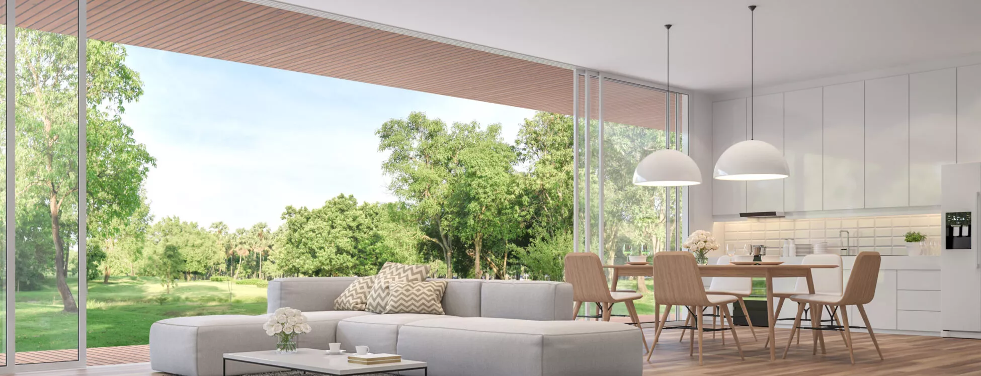 Un séjour avec un canapé, une table basse, une table et ses chaises, et une cuisine, dans une maison ouverte en pleine nature.