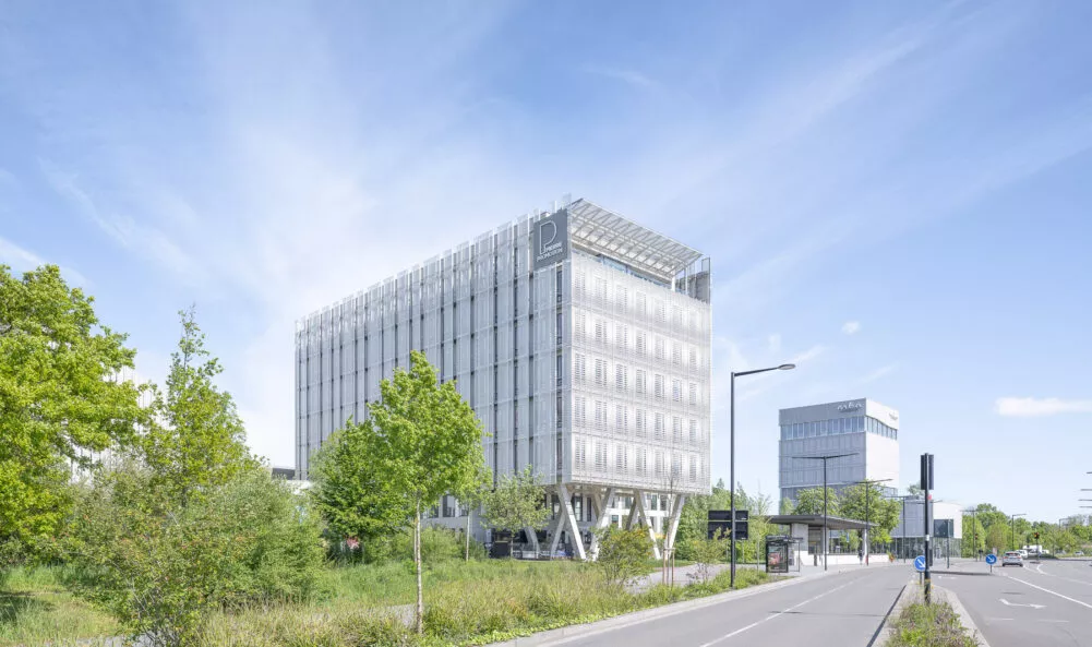 L'environnement extérieur, vue de la route, du siège social de Pierre Promotion situé ZAC de la Courrouze à Saint-Jacques-de-la-Lande, près de Rennes. Un ensemble de bureaux et de cellules commerciales réalisé par Pierre Promotion.