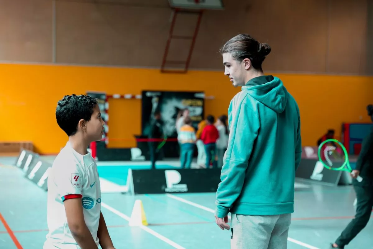 Un enfant discutant avec un adulte sur le tennis pendant l'OPEN en Quartiers by Pierre Promotion.