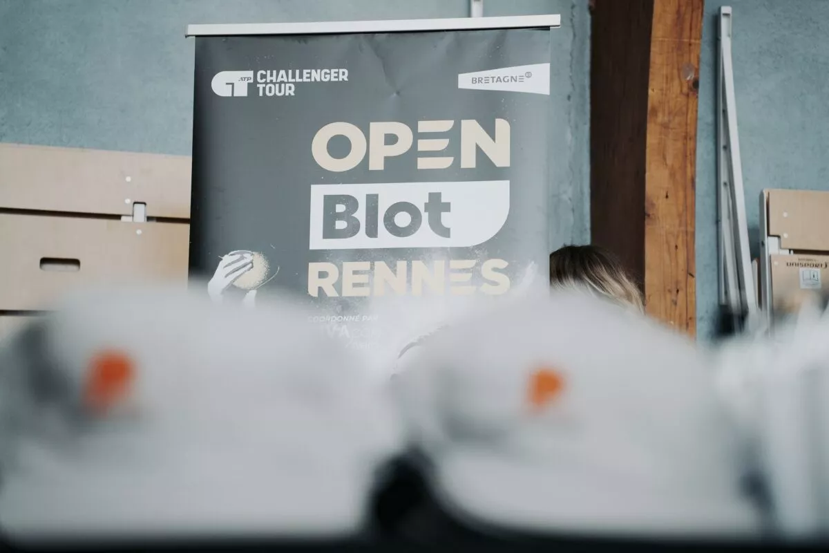 Casquette Pierre Promotion grise et flou avec une communication OPEN Blot Rennes en arrière-plan pendant l'Open en quartiers by Pierre Promotion.