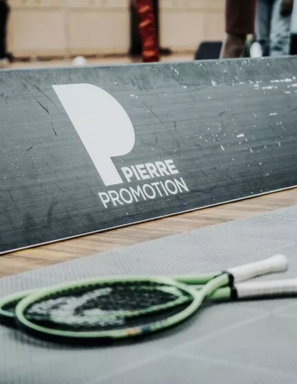 Deux raquettes de tennis posées sur le sol d'un court de tennis pendant l'OPEN en quartiers by Pierre Promotion