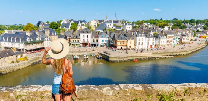 Femme sur la digue regardant vers la ville de Carnac bordée par la mer.